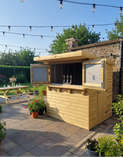 Timber Garden Bar with open serving hatch on a patio with festoon lights
